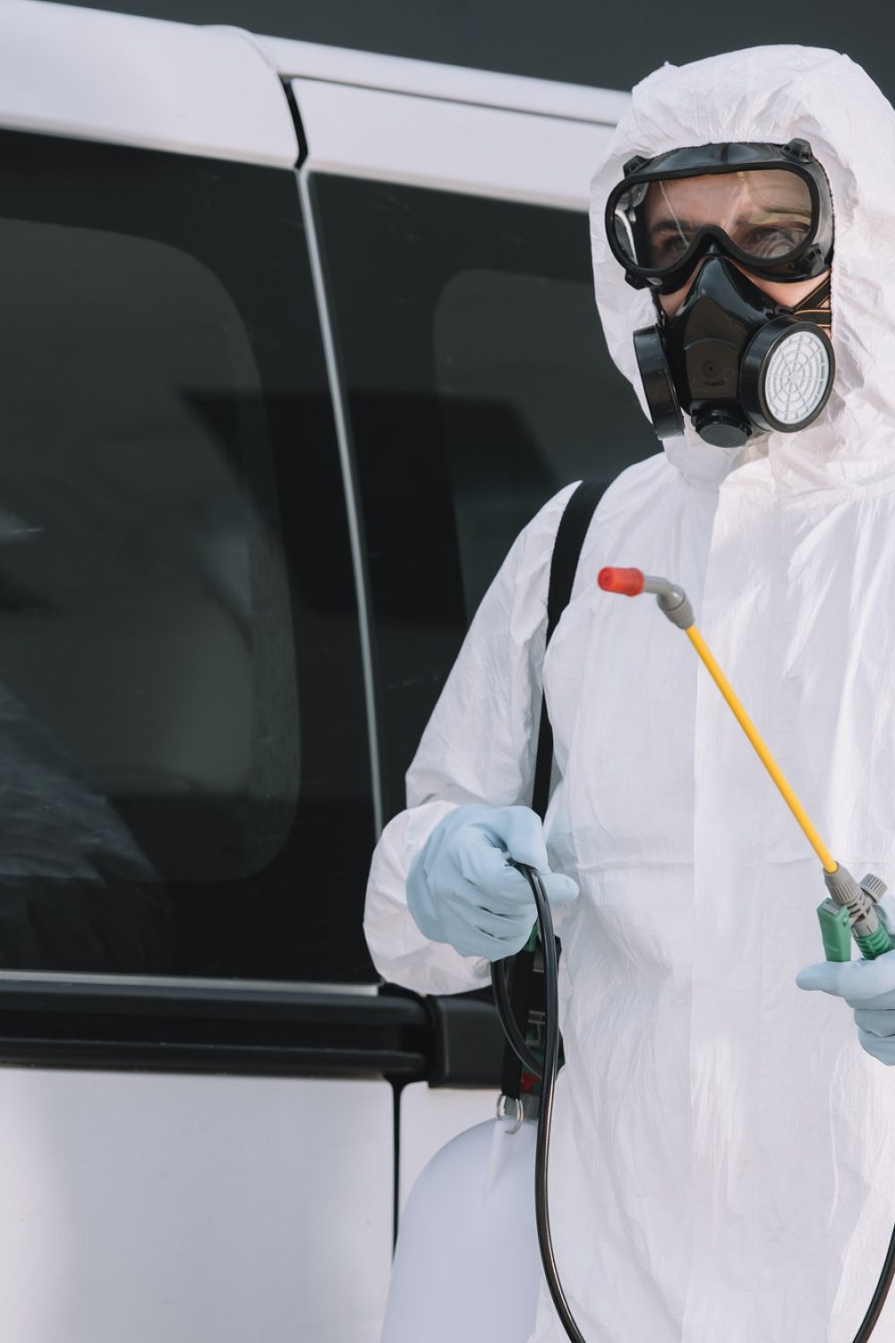 pest-control-worker-in-uniform-standing-near-car-on-street-and-holding-sprayer.jpg